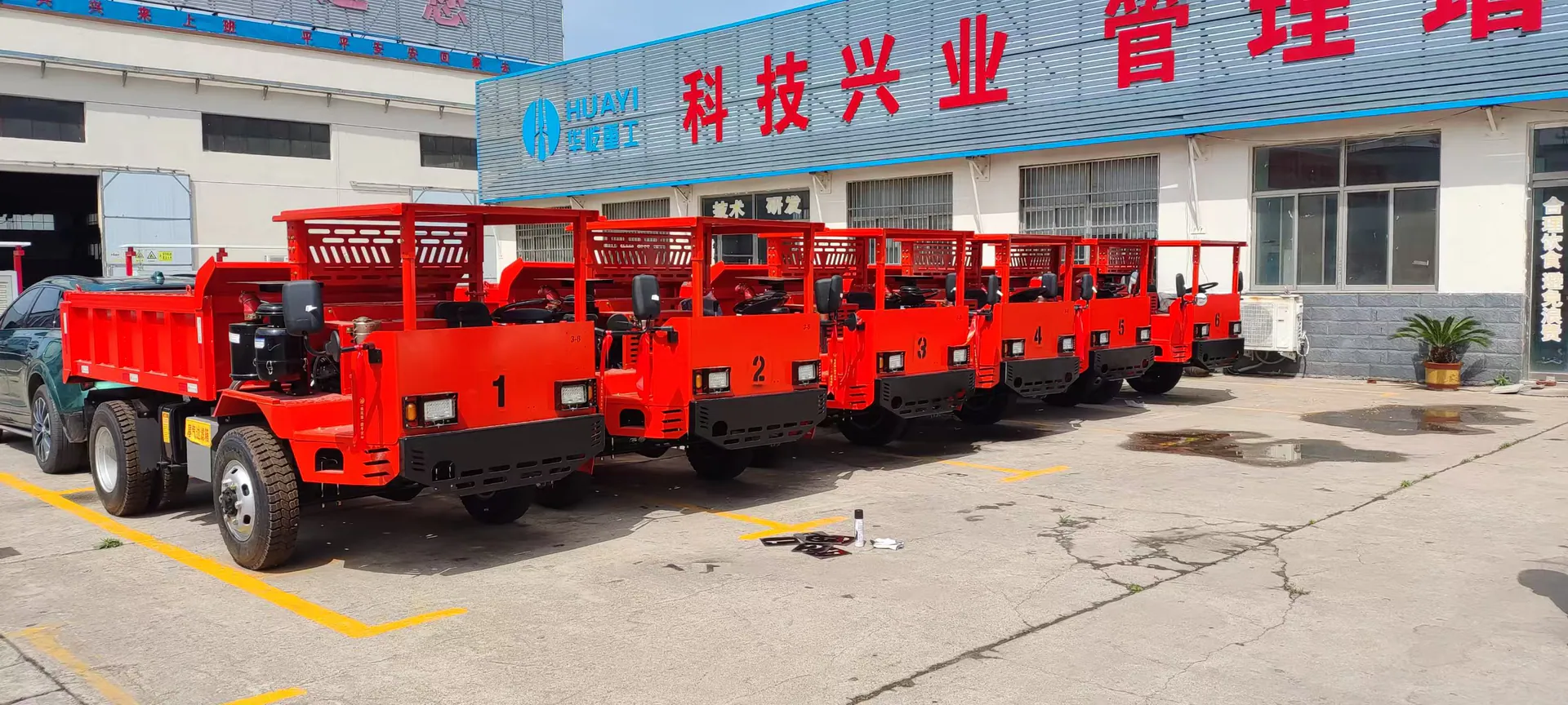 A row of red mining trucks displayed outside the factory.